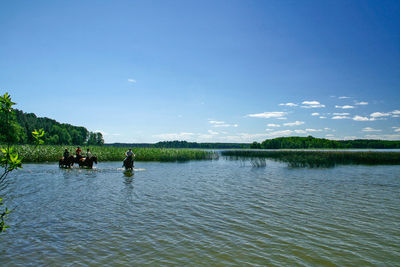 People on lake against sky