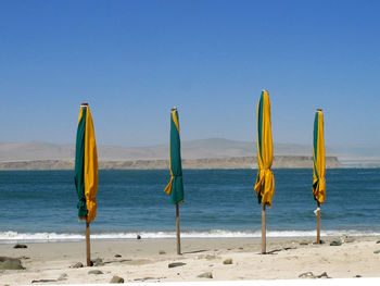 Deck chairs on beach against clear blue sky