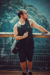 Young man looking away while standing outdoors