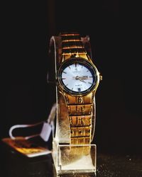 Close-up of clock on table against black background