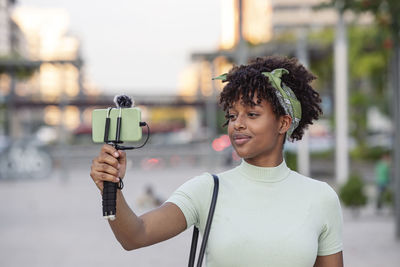 Portrait of young african american woman live streaming while walking around the city. 