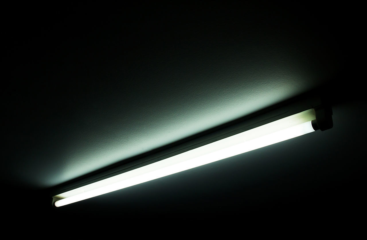 LOW ANGLE VIEW OF ILLUMINATED LIGHT BULB IN DARKROOM