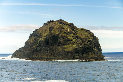 Rock formation on sea shore against sky