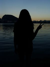 Rear view of woman standing by sea