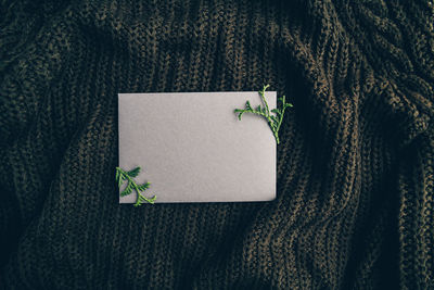 Directly above shot of blank paper with leaves over warm clothing