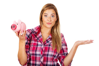 Portrait of woman holding piggy bank against white background