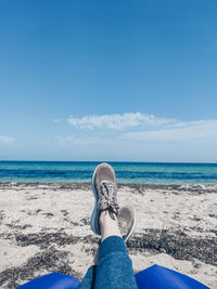 Low section of man on beach against sky