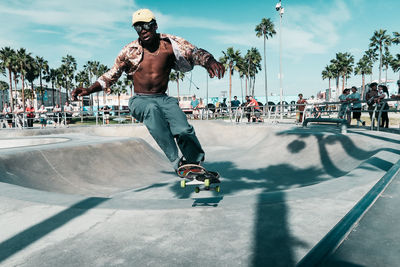 People skateboarding on street against sky