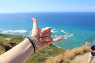 Close-up of hands on sea against clear sky
