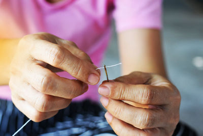 Close-up of woman holding sewing needle and thread