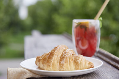 Aesthetic breakfast - french crust fresh croissant with  strawberry mojito cocktail at the terrace.