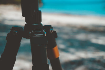 Close-up of hand holding camera at beach against sky