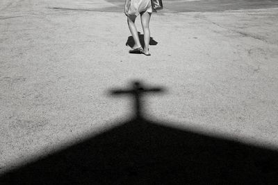A woman walks near the shadow of a church cross