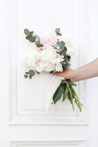 Cropped hand holding white flowers on door