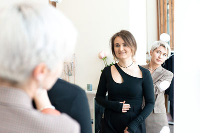 Young women choosing clothes at store, sales consultant offers wear