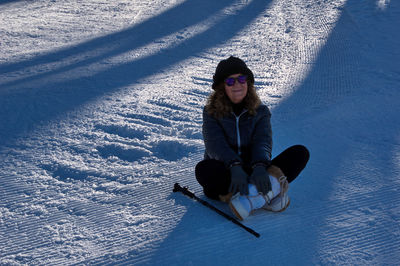 Portrait of young woman sitting on snow covered field