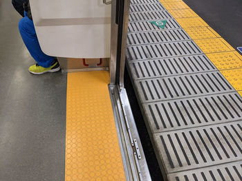 Low section of man standing on yellow platform