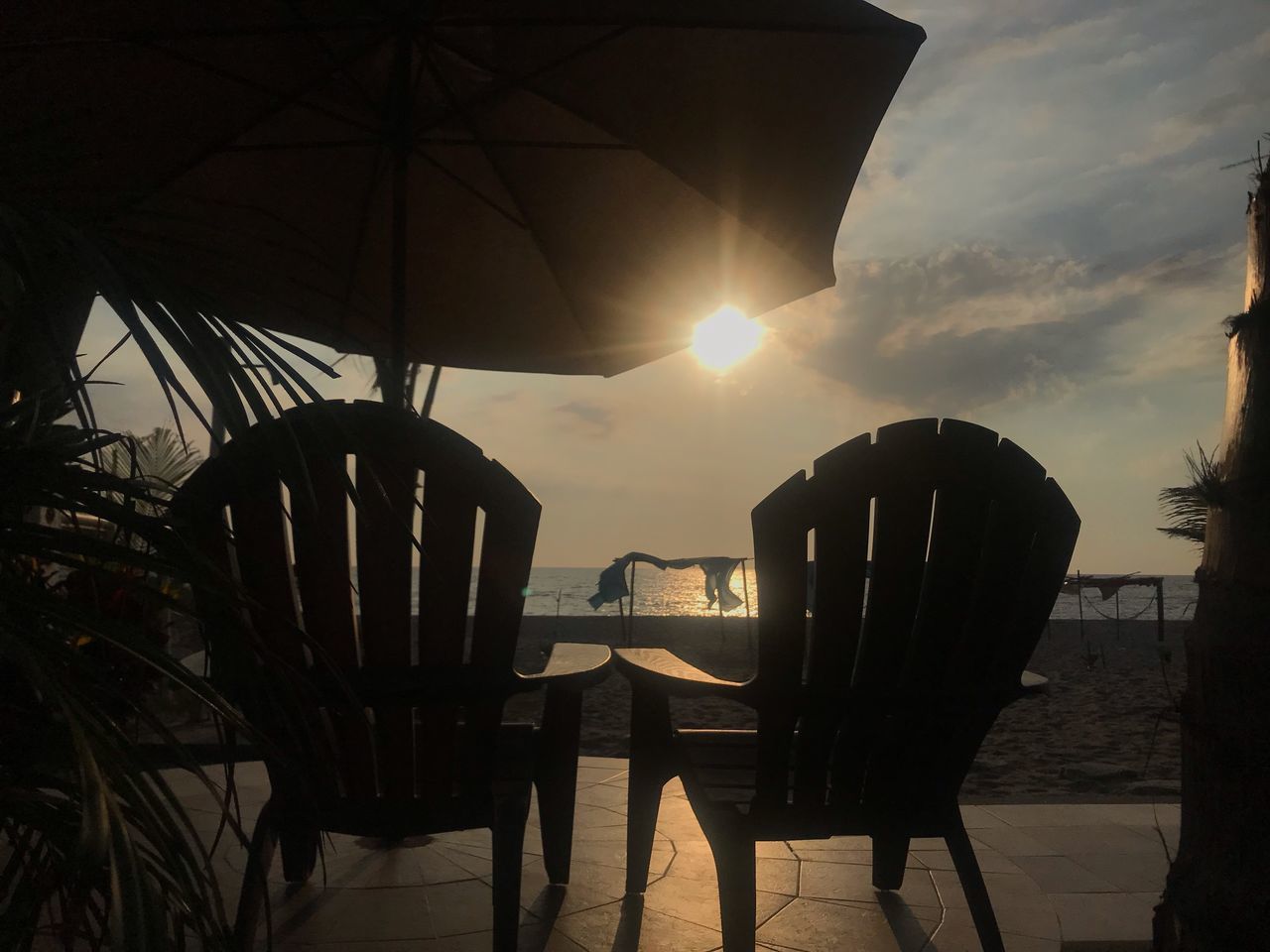 CHAIRS AND TABLES AT BEACH DURING SUNSET