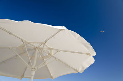Low angle view of white umbrella against clear blue sky