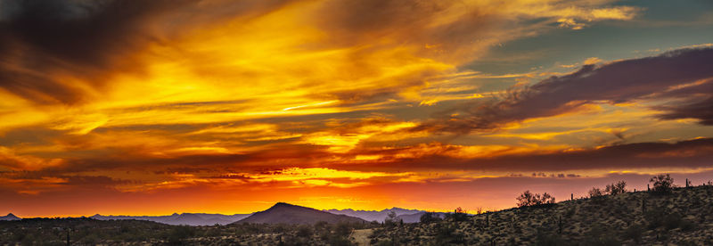 Scenic view of dramatic sky over silhouette mountains during sunset