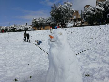 People on snow field against sky