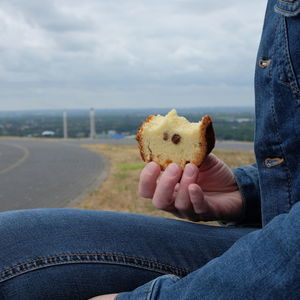 Midsection of person holding ice cream against sky