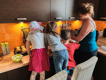 Rear view of family making food in kitchen at home