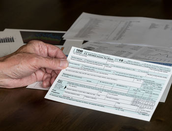 High angle view of man holding paper with text on table