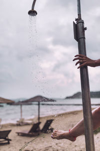 Low angle view of hand on beach against sky