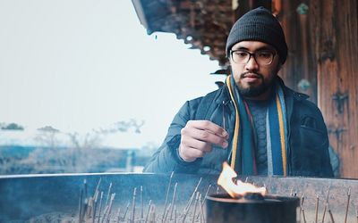 Young man holding incense at temple