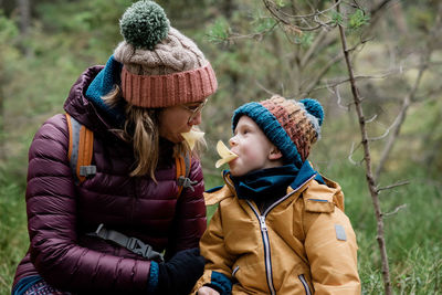 Mom and her son making silly faces whilst eating & hiking in winter