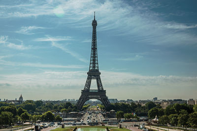 Communications tower in city against cloudy sky