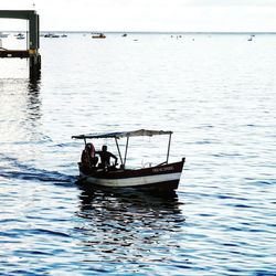 People in boat sailing on sea against sky
