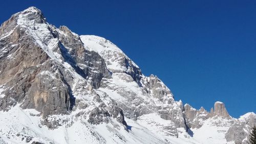 Low angle view of snowcapped mountain against blue sky