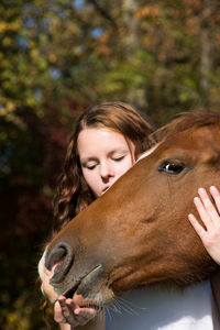 Young woman stroking horse at farm