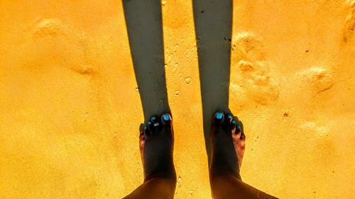 Low section of person standing on sand