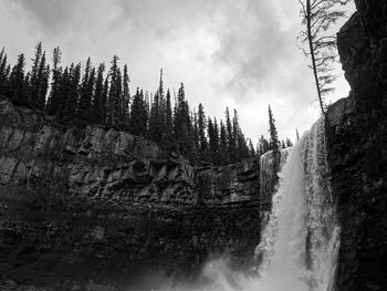 Scenic view of waterfall against sky in forest