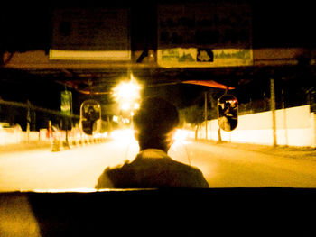 Rear view of man on illuminated street at night