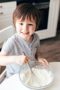 Cute boy stirring flour at home