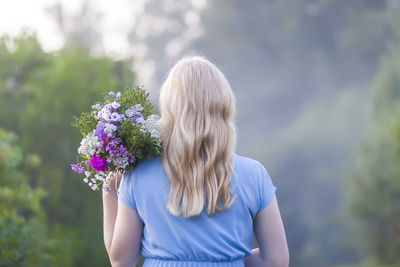 A girl in blue dress with a bouquet of wildflowers.