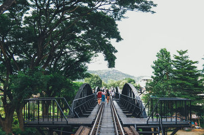 People on railroad tracks against sky