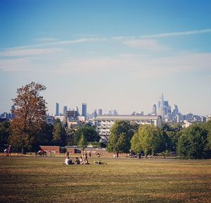 Park by buildings in city against sky
