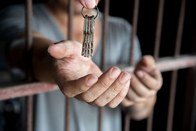 Cropped hand giving prisoner keys in prison cell