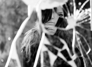 Close-up of woman's reflection in broken glass