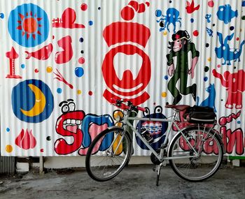Bicycle parked against graffiti wall
