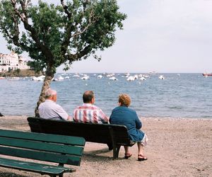 Rear view of couple sitting on bench at beach