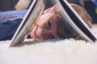 Portrait of smiling boy lying down on carpet