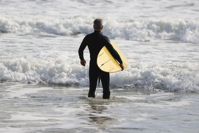 Rear view of male surfer standing in sea