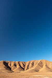 Scenic view of desert against clear blue sky