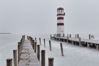 Lighthouse on sea against clear sky